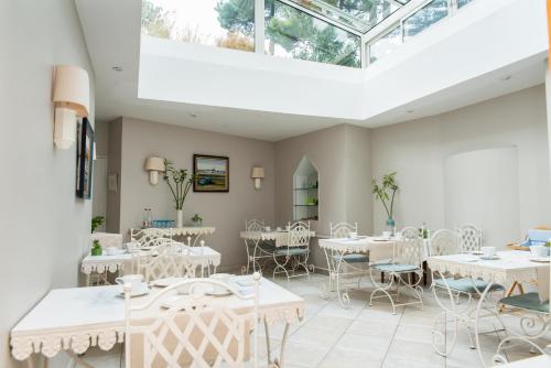 a dining room with white tables and chairs at Hôtel Lutétia & Spa in La Baule