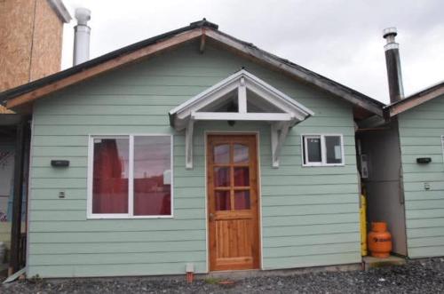 a green house with a door and a window at Paraiso Patagonico in Chaitén