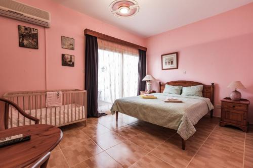 een slaapkamer met roze muren en een bed en een tafel bij Villa Papaya Residence in Paphos City
