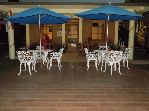 a group of tables and chairs with blue umbrellas at Hotel y Cabañas Quinta Los Cipreses in Atlatlahucan