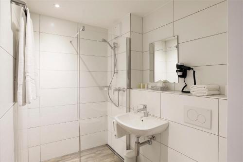 a white bathroom with a sink and a mirror at Hotel Work Life Residence am Bahnhof in Winterthur