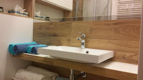 a bathroom with a white sink and wooden wall at PANORAMA KOSZALIN in Koszalin