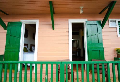 a pink and green house with green doors and a porch at Hacienda Juanita in Maricao