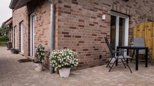 a brick building with a table and chairs and flowers at WeststrandPur in Norderney