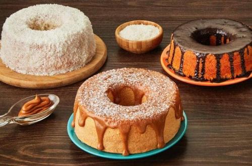 two cakes on plates on a wooden table at Pousada Arraial Suites in Arraial d'Ajuda