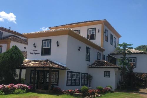 un grand bâtiment blanc avec des fenêtres noires et une cour dans l'établissement Pousada Vovô Chiquinho, à Tiradentes
