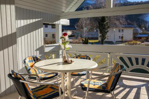 a white table and chairs on a balcony with a vase of flowers at Ferienwohnungen Kapp in Tröpolach