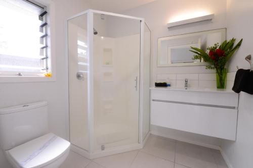a white bathroom with a shower and a toilet at Makayla Palms in Rarotonga