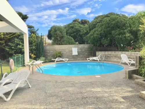 a swimming pool with two chairs and a table at Departamento Alto Libertad Meseta Coraceros in Viña del Mar