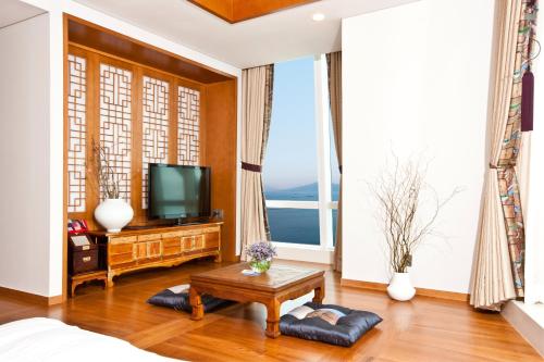 a living room with a television and a large window at Sono Calm Yeosu in Yeosu