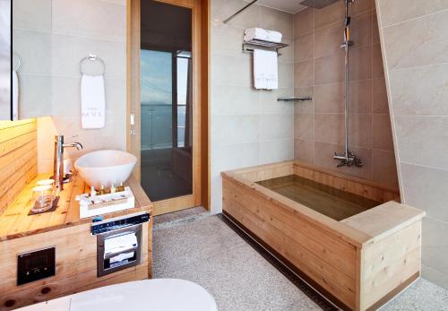 a bathroom with a tub and a sink at Sono Calm Yeosu in Yeosu