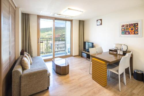 a living room with a couch and a table and a desk at Sono Belle Cheonan in Cheonan