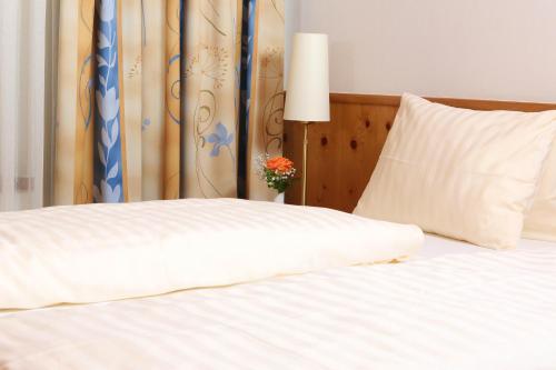 a white bed with a pillow and a vase with flowers at Gasthof Engelhof in Gmunden