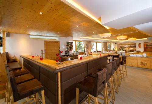 a bar in a kitchen with a bunch of chairs at Hotel Alpina in Rauris