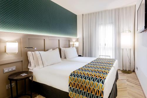 a hotel room with a large bed and a green wall at Eurostars Puerta Real in Granada