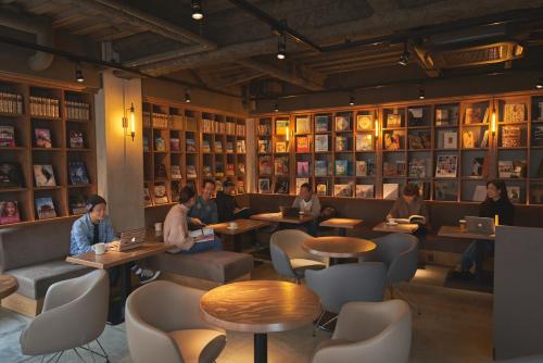 a group of people sitting at tables in a restaurant at Busoan Library & Hostel in Machida