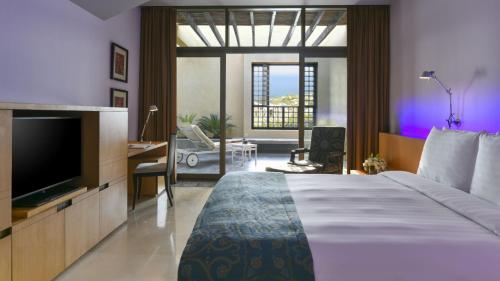 a hotel room with a bed and a television at Kempinski Hotel Ishtar Dead Sea in Sowayma