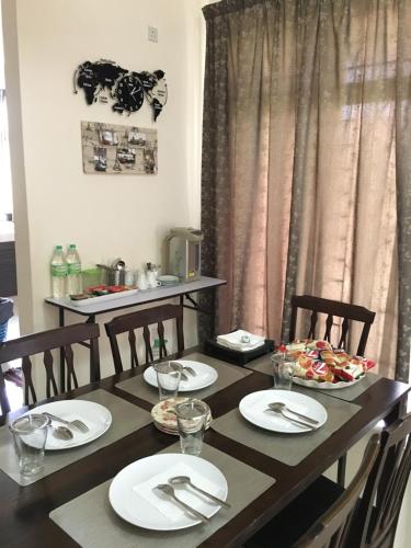 a dining room table with white plates and chairs at Putrajaya 1808 Homestay in Putrajaya