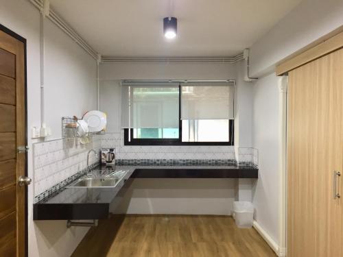 a white kitchen with a sink and a window at Hello House in Krabi town