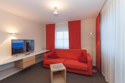 a living room with a red couch and a tv at Alpenresidenz Buchenhöhe in Berchtesgaden