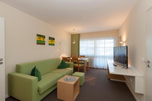 a living room with a green couch and a table at Alpenresidenz Buchenhöhe in Berchtesgaden