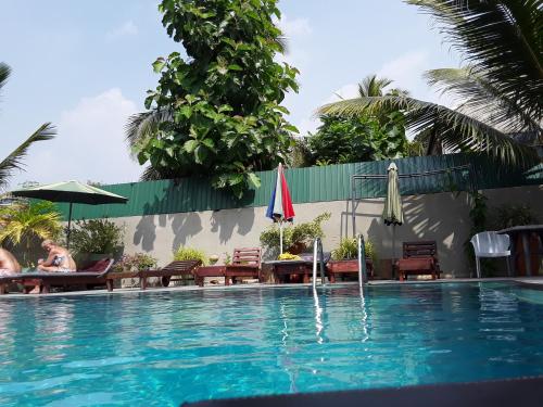 a swimming pool with chairs and umbrellas next to at Karl Holiday Bungalow in Kalutara