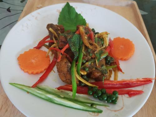 a plate of food with meat and vegetables on a table at Amaretto Hostel in Surat Thani