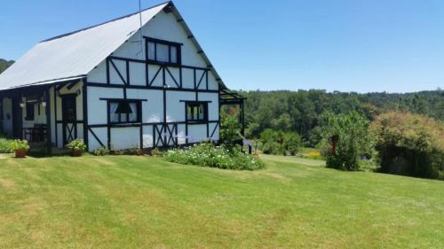 una casa bianca e nera su un prato di Woodcutters Guest House a Haenertsburg