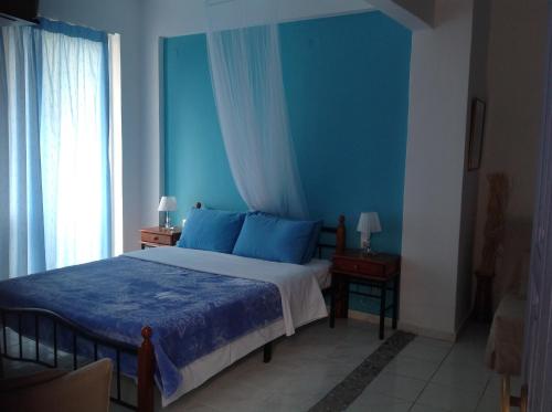 a bedroom with blue walls and a bed with blue sheets at Panorama in Skafidia
