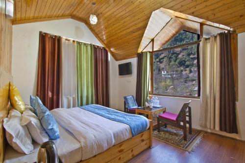 a bedroom with a large bed and a window at The Cedar Cottages & Independent Villa & Kitchenette Fireplace Tandoor & BBQ in Manāli