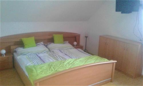 a bedroom with a wooden bed with green pillows at Apartment MASCH in Arriach