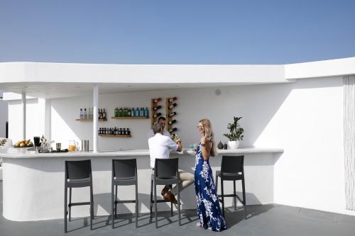 un homme et une femme debout à un bar dans une cuisine dans l'établissement Santorini Princess Presidential Suites, à Akrotiri