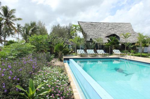 a pool at a resort with chairs and flowers at Villa Dahl Beach Resort in Dar es Salaam