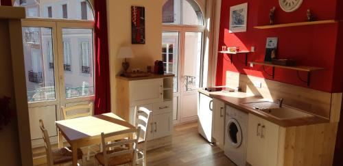コトレにあるRésidence Eugénieの赤い壁のキッチン(テーブル、洗濯機付)