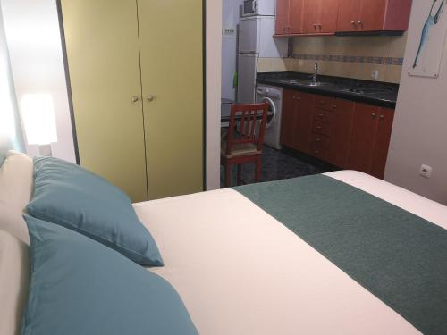 a bedroom with a bed with a blue pillow and a kitchen at Estudios Dalia in Vecindario