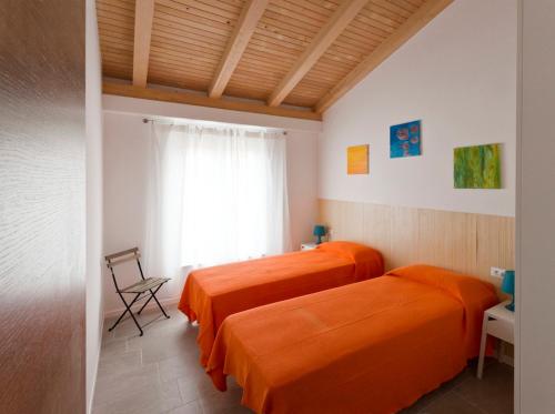 twee bedden in een kamer met oranje lakens bij Giotto Holiday Houses in Vrsi