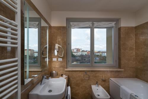 a bathroom with a sink and a tub and two windows at Hotel Palazzo San Lorenzo & Spa in Colle Val D'Elsa