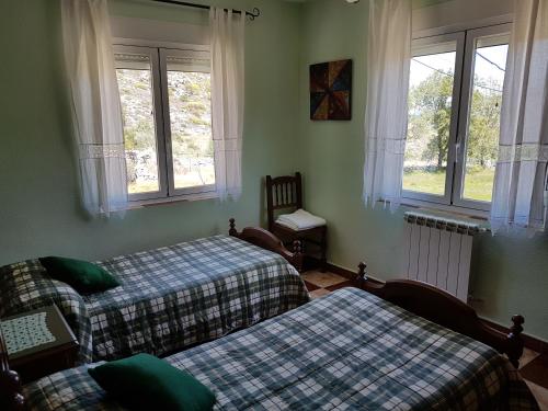 a bedroom with two beds and a couch and windows at Casa Rural Las Chorreras in Navalguijo