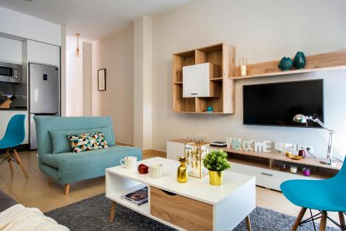 sala de estar con mesa blanca y silla azul en HSH Suites Metropol, en Sevilla