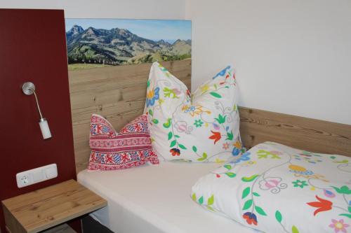 a bed with three pillows and a painting on the wall at Berggasthaus Kraxenberger in Brannenburg