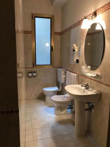 a bathroom with a sink and a toilet and a mirror at Hotel San Felice in Bologna