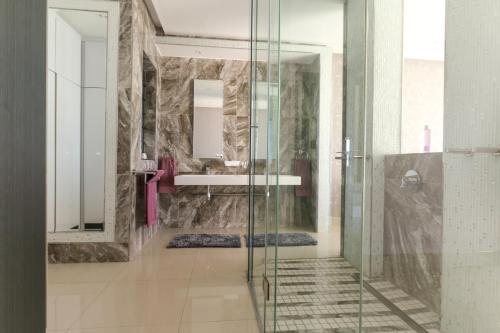 a bathroom with a glass shower and a sink at GORDON's SHORE LUXURY APARTMENTS - Solar Powered in Gordonʼs Bay