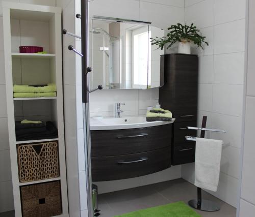ein Bad mit einem Waschbecken und einem Spiegel in der Unterkunft A l'Ancien Moulin in Lampertheim