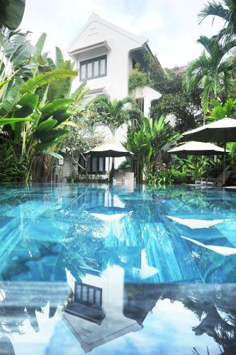 a swimming pool with blue water in front of a house at East West Villa in Hoi An