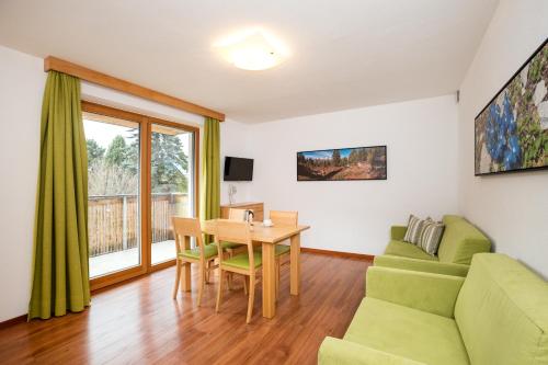 a living room with a green couch and a table at Residence Aichner in Brunico