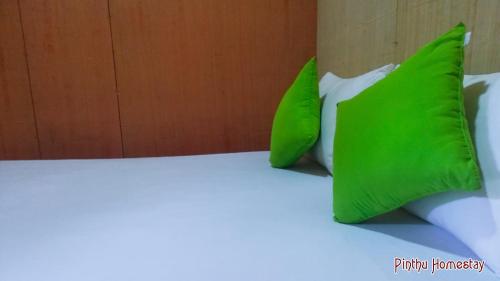 two green pillows sitting on top of a bed at Pinthu Home Stay in Sigiriya
