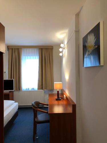 ein Hotelzimmer mit einem Bett und einem Schreibtisch mit einer Lampe in der Unterkunft Hotel Mirabell in Erlangen