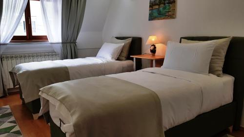 a hotel room with two beds and a table with a lamp at Apartment Cobanija in Sarajevo