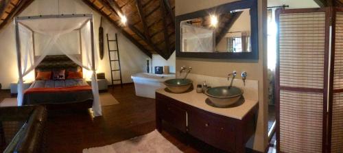 a bathroom with two sinks and a bed in a room at Rhinos Rest in Marloth Park
