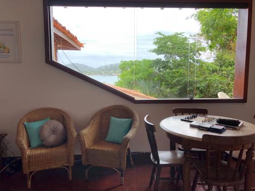 a room with a table and chairs and a large window at Pousada Encanto de Búzios in Búzios